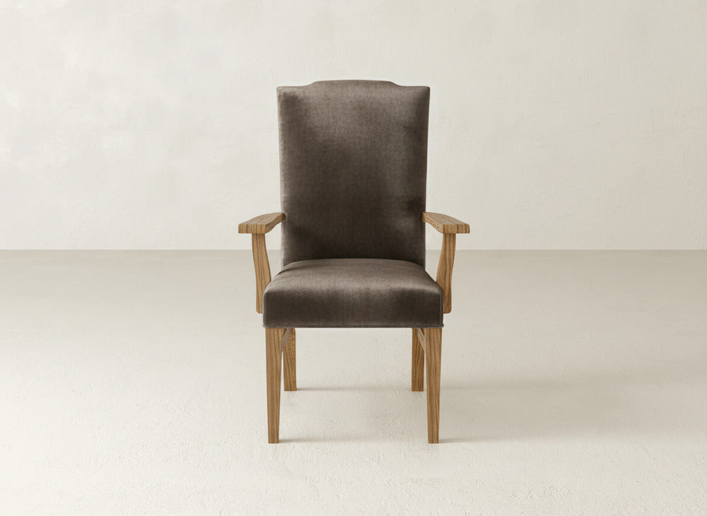 The James+James Hadley Arm Dining Chair features a wooden frame with a high, cushioned back and seat upholstered in dark brown fabric, shown against a plain light background.