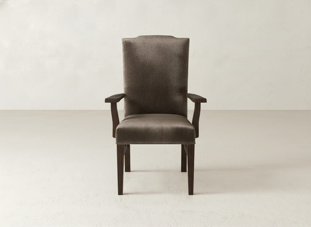 A straight-on view of the Hadley Arm Dining Chair by James+James, featuring dark brown upholstery with wooden legs and arms, set against a plain, light background.