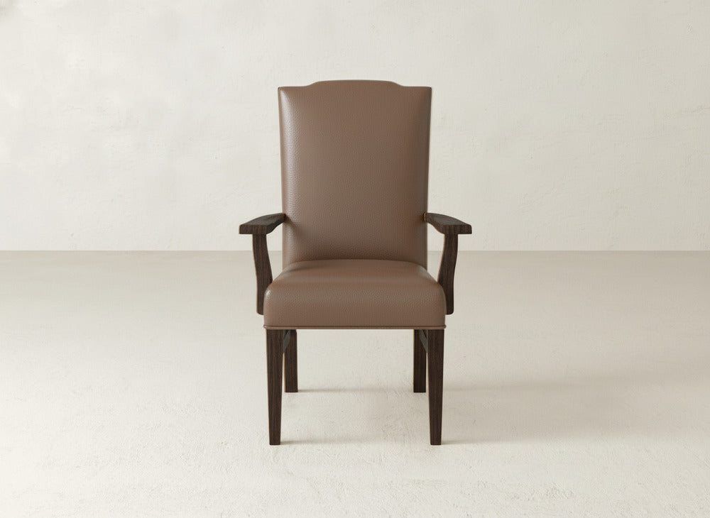 The James+James Hadley Arm Dining Chair, featuring a brown finish and wooden legs and armrests, is centered against a plain, light-colored wall and floor.