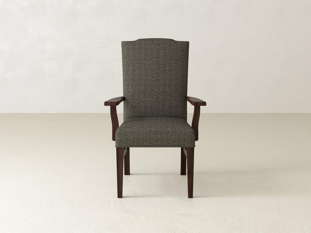 A Hadley Arm Dining Chair in Tobacco by James+James is centered against a plain off-white background. The chair features a high back and boasts a simple, elegant design with dark gray upholstery complemented by wooden arms and legs.