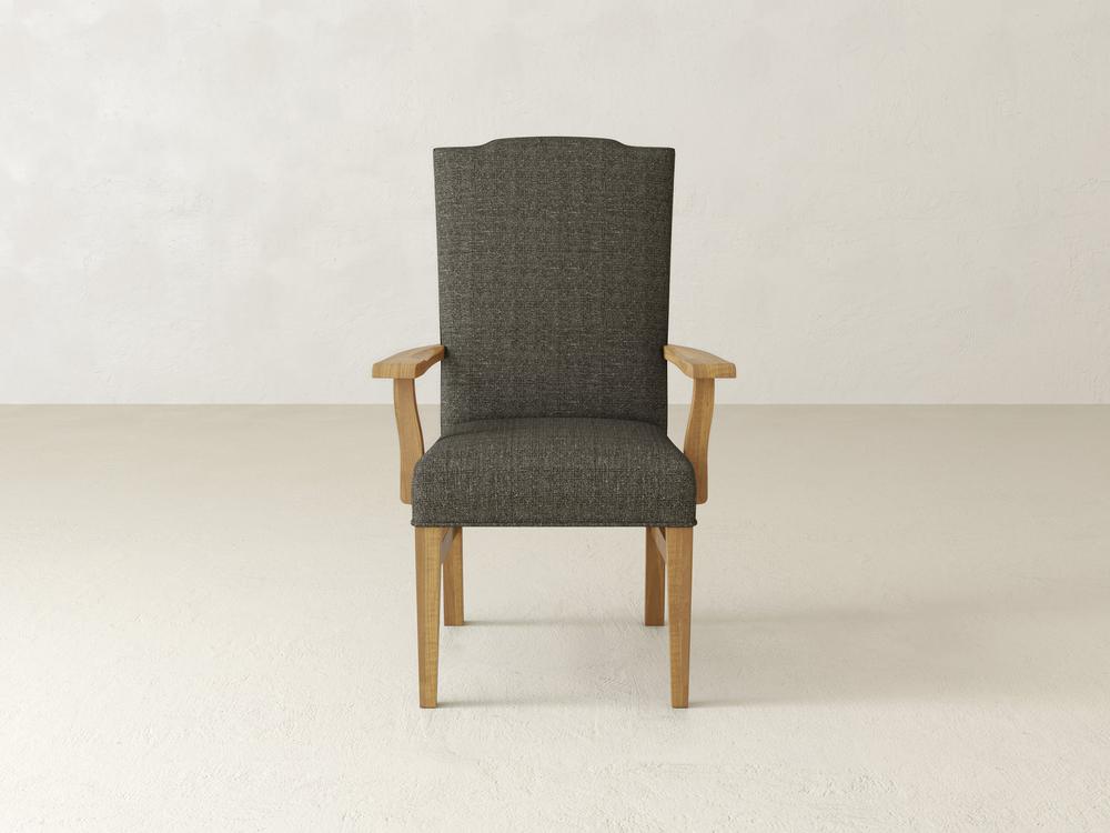 A Hadley Arm Dining Chair in the Harvest Wheat finish by James+James, featuring a tall backrest and armrests, upholstered in dark gray fabric, is placed against a plain, light-colored background.