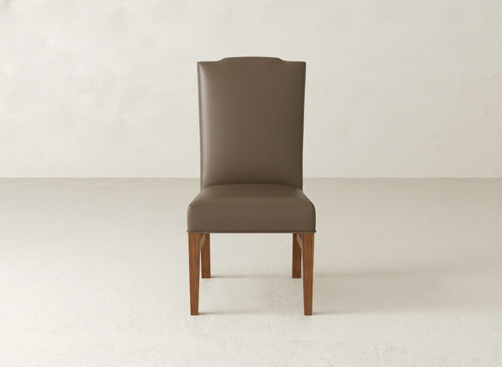 The Hadley Side Dining Chair by James+James, featuring a brown upholstered high back and wooden legs, is centered against a plain light background. Its modern design brings simple elegance to any dining room.