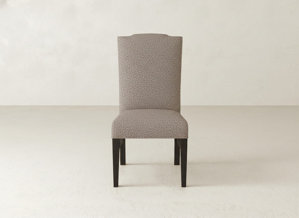 The Hadley Side Dining Chair by James+James features plush upholstery and dark wooden legs, standing on a light floor against an off-white wall—an elegant addition to any space.