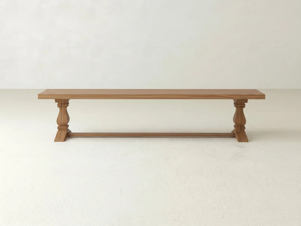 The Heirloom Bench - Oat on Oak by James+James features a rectangular seat, turned legs, and a support bar, shown against a light-colored wall and floor.