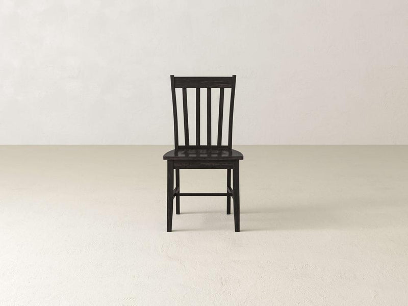 The Henry Dining Chair - Tobacco by James+James features a wooden design with a high backrest adorned with vertical slats. The chair boasts a dark wood finish and four straight legs, showcasing simple and sturdy construction. Its flat seat complements the classic and minimalist design, as shown from an angled rear view.