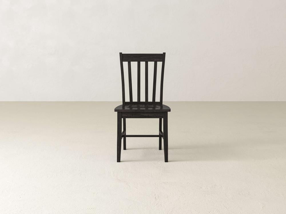 The Henry Dining Chair - Tobacco by James+James features a wooden design with a high backrest adorned with vertical slats. The chair boasts a dark wood finish and four straight legs, showcasing simple and sturdy construction. Its flat seat complements the classic and minimalist design, as shown from an angled rear view.