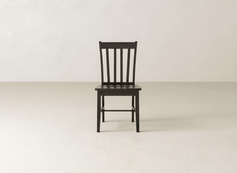 A single James+James Henry Dining Chair with a classic slat-back design is centered in a bright, empty room with smooth floors and plain walls, creating an atmosphere of refined dining simplicity.