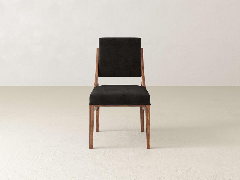 A wooden chair with a black cushioned seat and backrest, placed centrally against a plain, off-white background. The chair has a simple, modern design with natural wood grain visible on the frame.