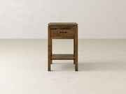 The Jensen 1 Drawer Nightstand by James & James, crafted from solid maple hardwood, showcases a rustic finish with modern simplicity. It features one drawer and an open shelf beneath it, all set against a plain light-colored background in its minimalist design.