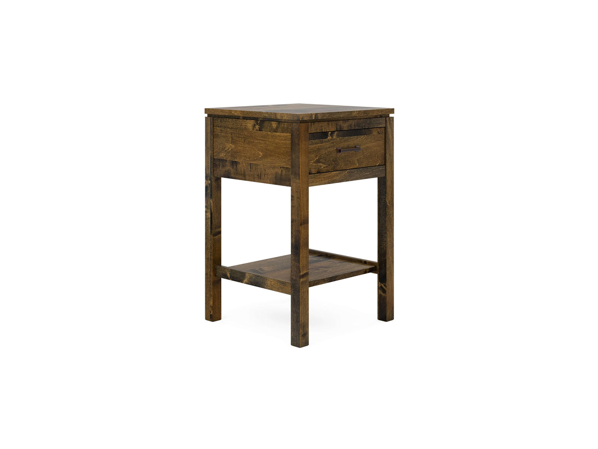Wooden side table with a single drawer and a lower shelf. The table features a dark wood finish and simple, straight lines, giving it a rustic appearance. The drawer has a handle, and the table stands on four sturdy legs.