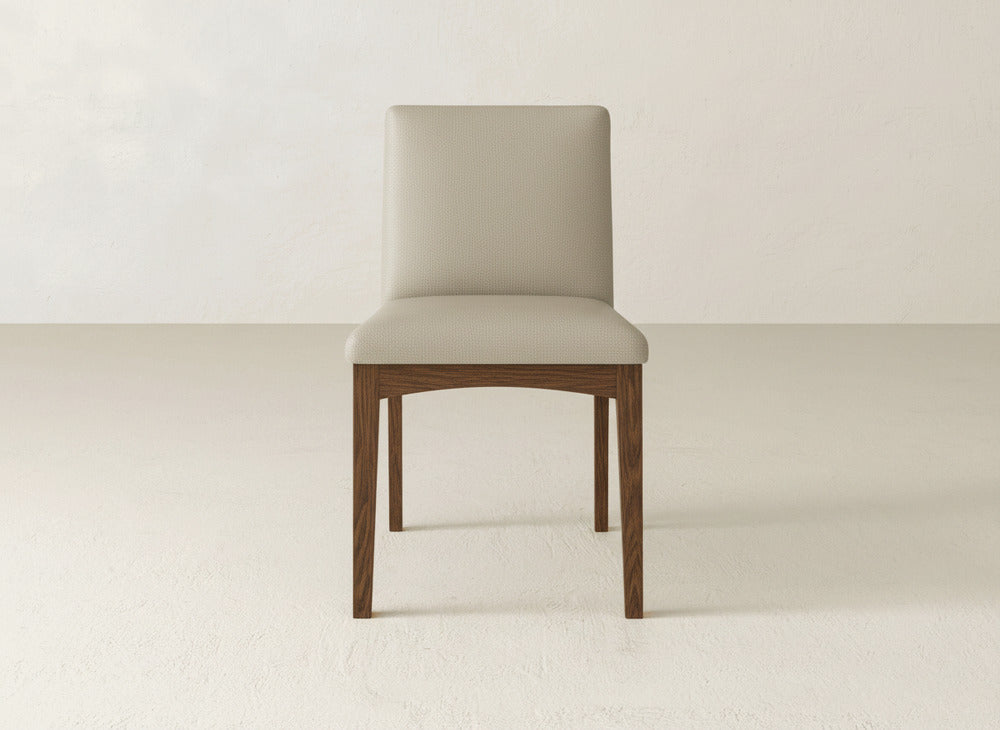 The James & James Klein Dining Chair showcases beige upholstery, a straight backrest, and maple legs, set on a light textured floor with an off-white backdrop.