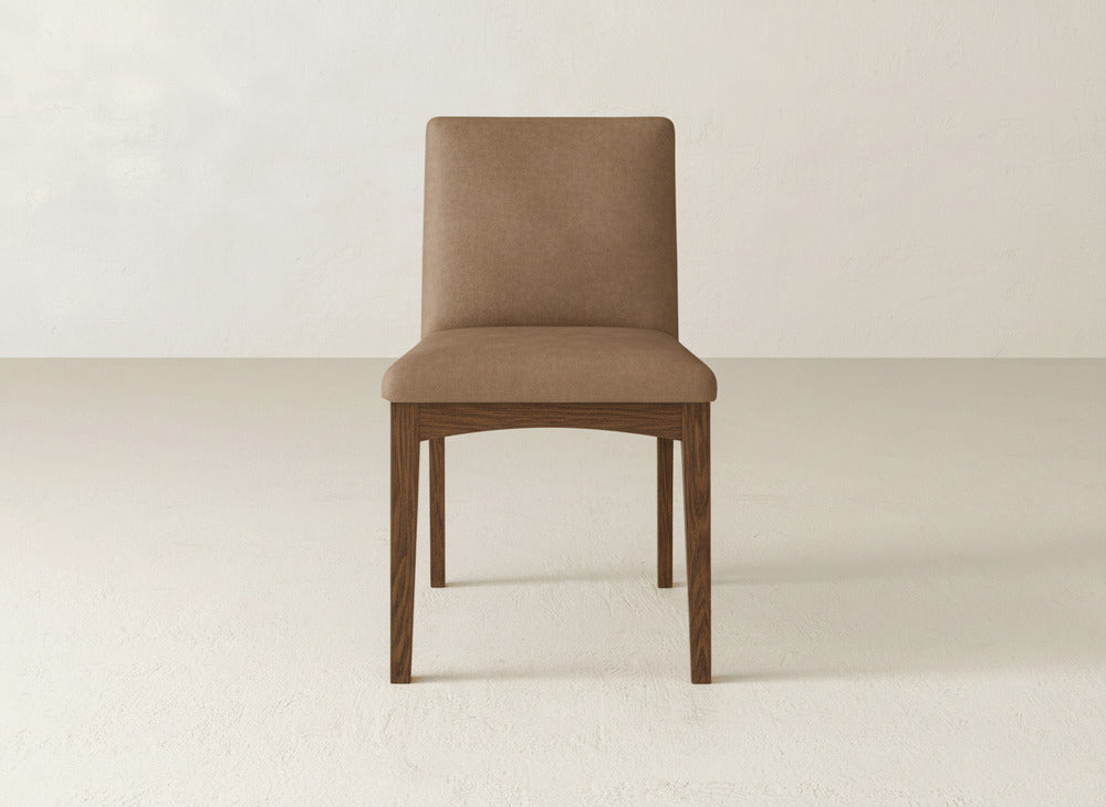 The Klein Dining Chair by James & James features a brown upholstered seat, straight back, and sleek maple legs—an elegant focal point for minimalist spaces with light walls and flooring.