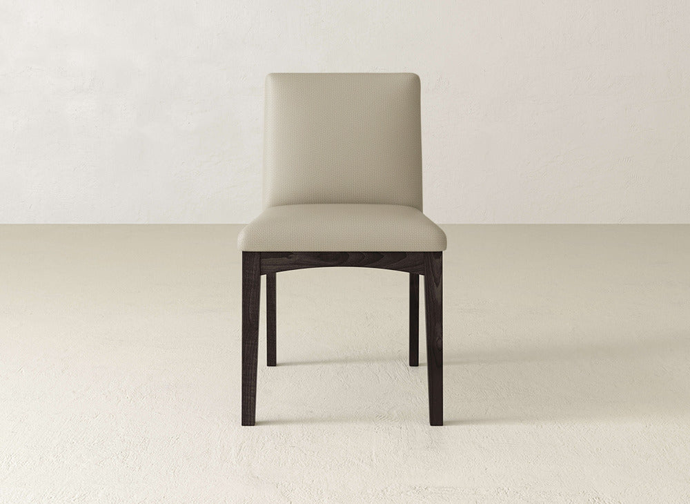 The Klein Dining Chair by James & James features beige upholstery, a straight backrest, and maple wooden legs, shown on a light textured floor against a plain wall.