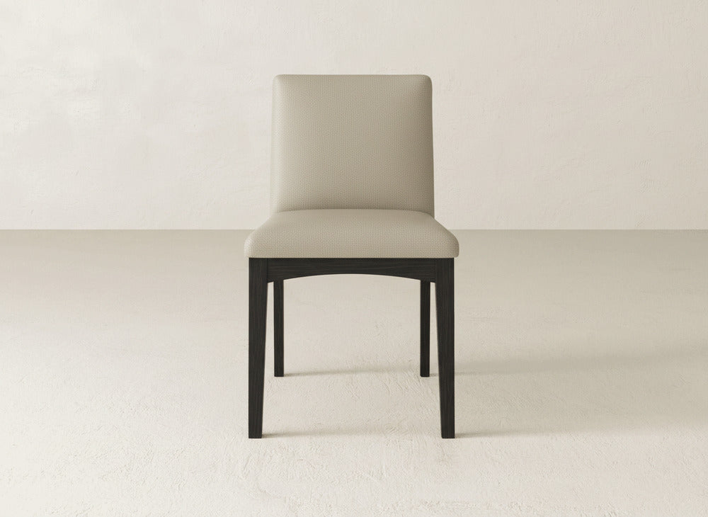 The James & James Klein Dining Chair, featuring a light beige upholstered seat and backrest with dark maple legs, is centered against a plain off-white background.