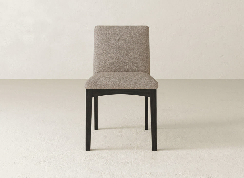 The Klein Dining Chair from James & James features textured light beige upholstery and maple legs, styled on a light floor against an off-white wall for a modern, contemporary feel.
