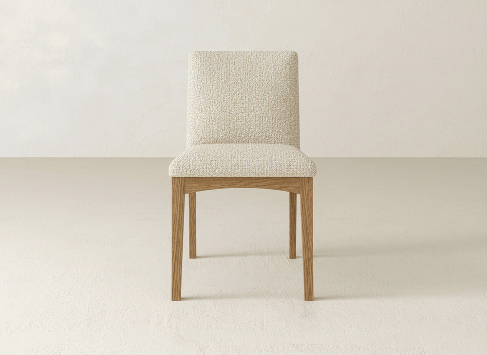 The James & James Klein Dining Chair offers a light beige textured upholstered seat and backrest with elegant maple wooden legs, perfect for minimal, neutral spaces.