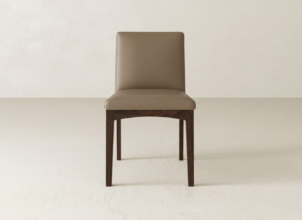 The James & James Klein Dining Chair features a simple, modern design with a light brown cushioned seat and backrest and dark maple wooden legs, perfect for minimal, light-colored spaces.