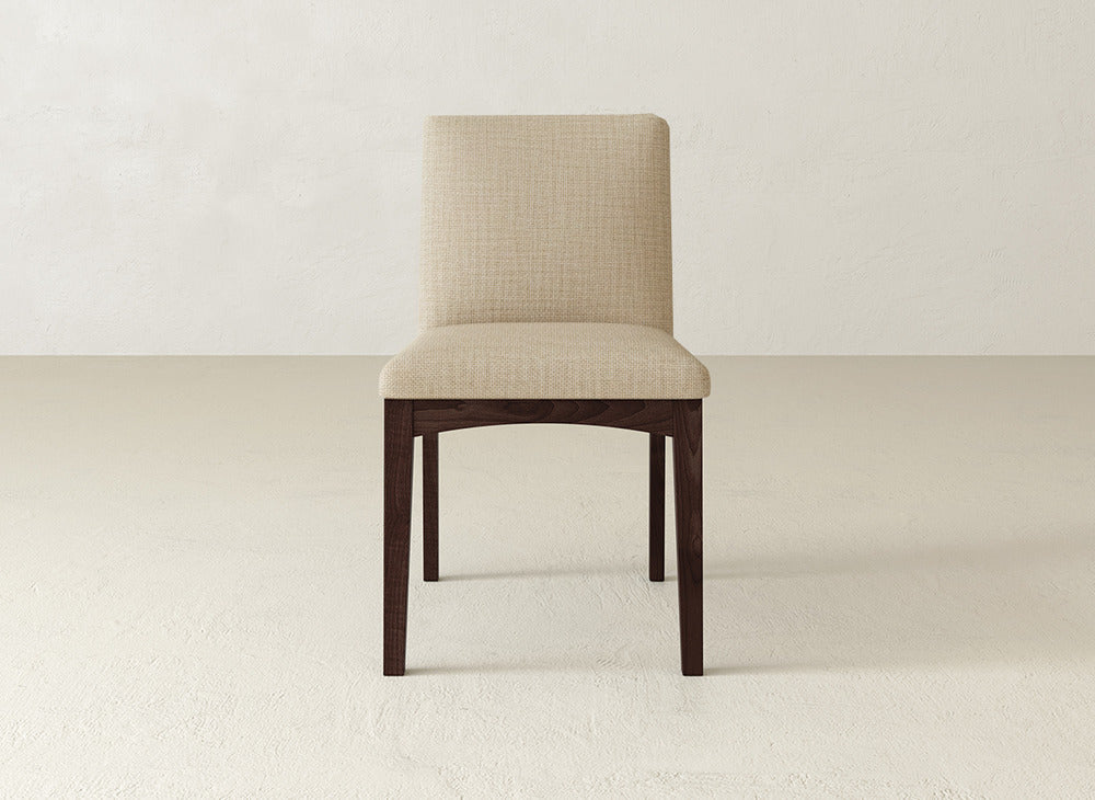 The James & James Klein Dining Chair boasts a simple modern design with a light beige upholstered seat and maple wooden legs, making it perfect for adding style to any neutral room.