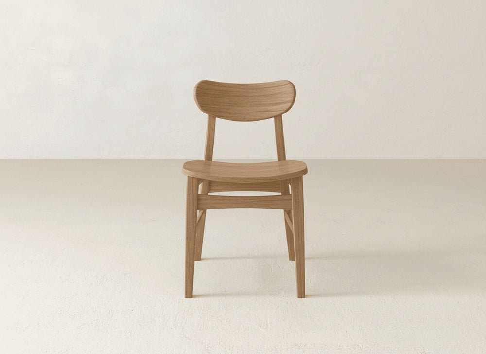 The James+James Lynn Dining Chair showcases a curved backrest and seat in solid maple hardwood, offering minimalist mid-century modern style and heirloom American craftsmanship.