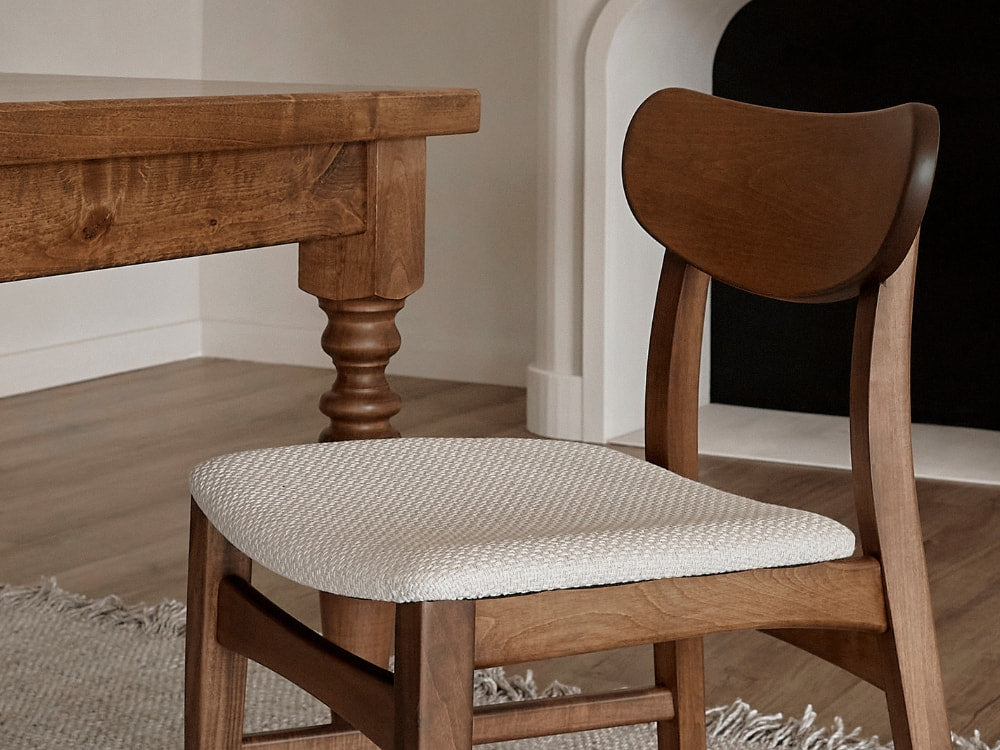 The James+James Oatmeal - Textured Linen Swatch chair sits beside a table, offering a timeless aesthetic ideal for classic interiors.