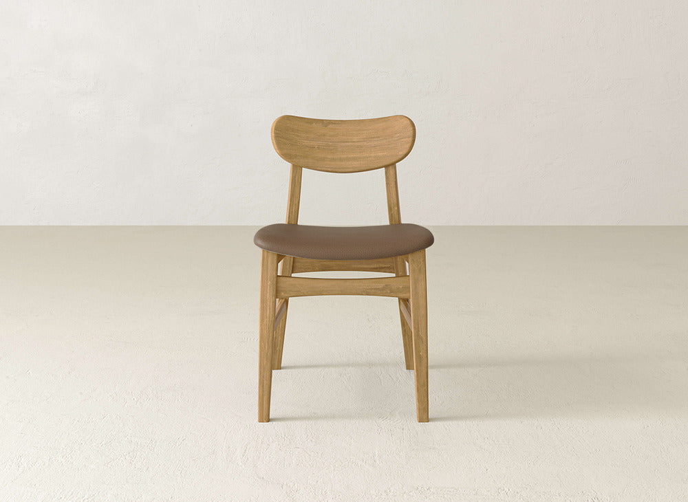 The Lynn Upholstered Dining Chair by James+James features a curved backrest and brown cushioned seat crafted from maple wood, blending classic charm with modern elegance for your dining space.