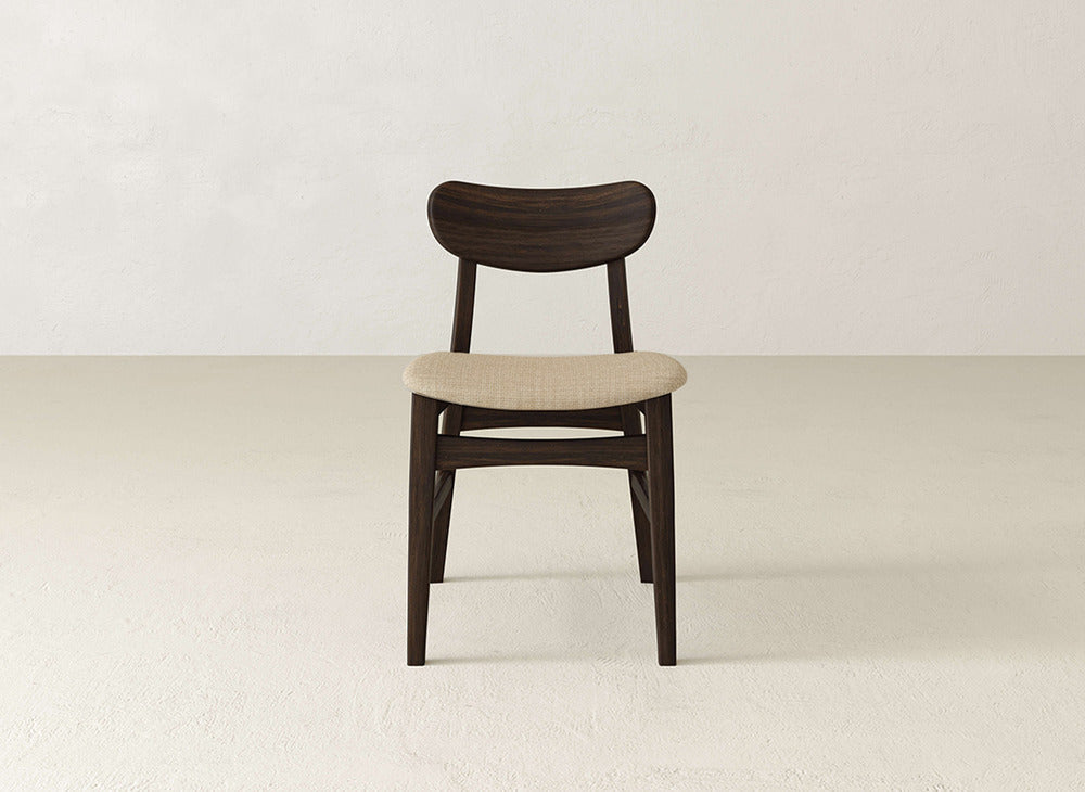The Lynn Upholstered Dining Chair by James+James showcases a dark brown maple wood frame and light beige cushioned seat, adding modern sophistication to any space.