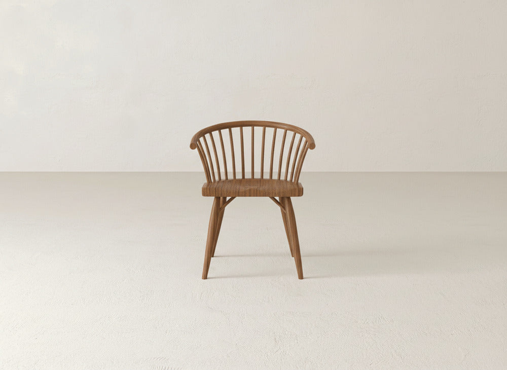 The James+James Maria Dining Chair, featuring a curved backrest and vertical slats, is centered in a minimalist room with light walls and flooring.