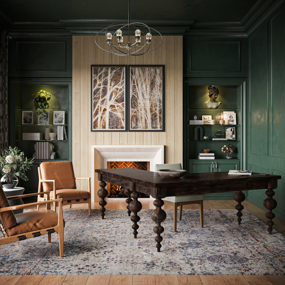A cozy study with dark green walls features the Olivia Corner Desk in Tobacco by James+James, two brown chairs, and a fireplace. Bookshelves flank the fireplace with two framed artworks above it. A patterned rug covers the floor, and a modern chandelier hangs overhead.