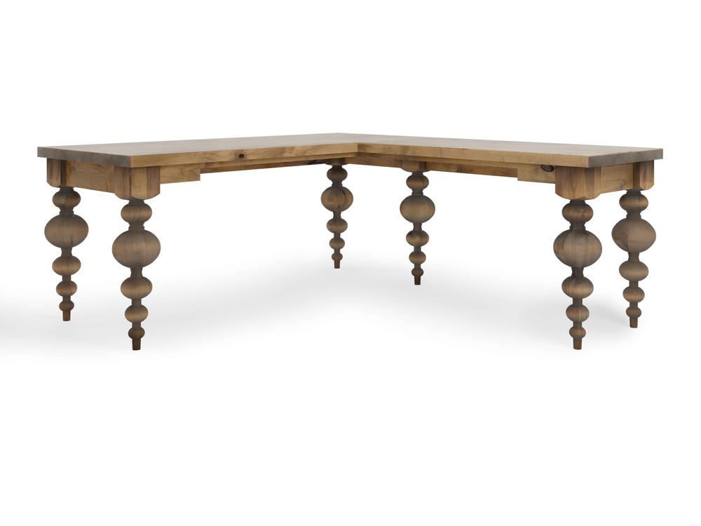 The Olivia Corner Desk - Harvest Wheat by James+James is an L-shaped wooden desk featuring ornate, intricately turned legs. Boasting a natural wood finish, it showcases a rustic and vintage style. This elegant and functional design is perfect for fitting into a corner space in any room.