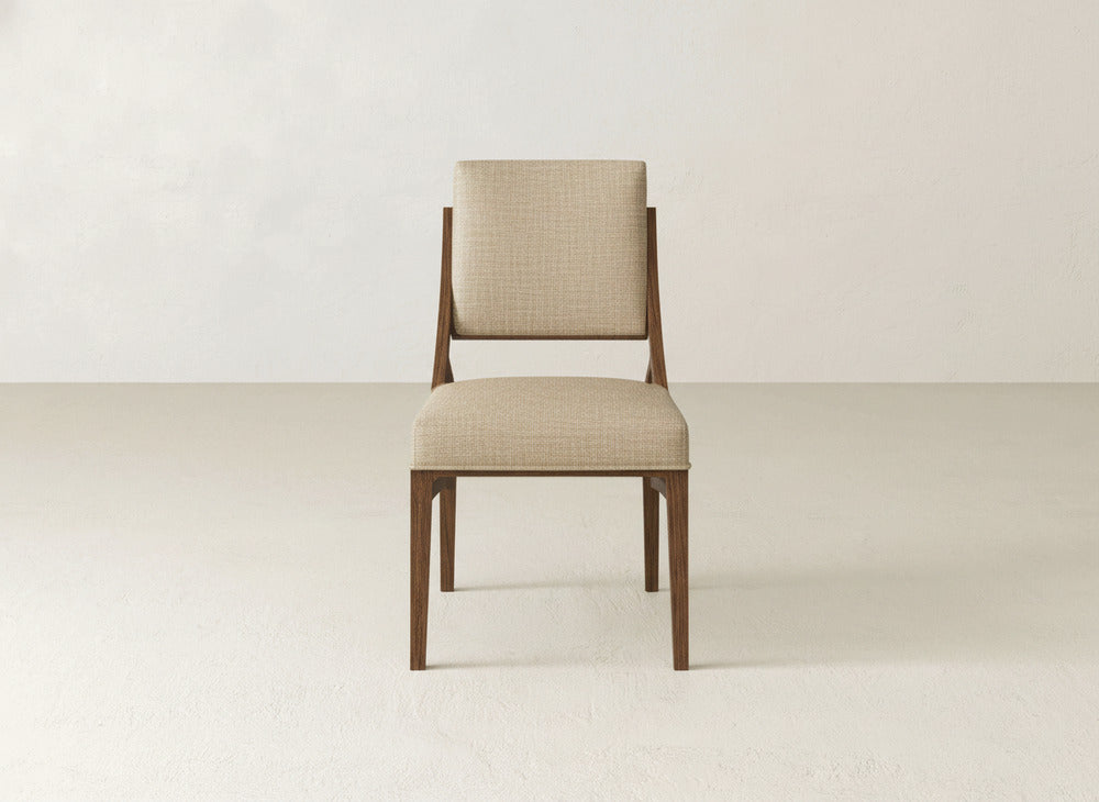 The James+James Quinn Dining Chair features beige upholstery and a wooden frame. Its modern, minimalist design with clean lines makes it an ideal addition to any contemporary dining room.