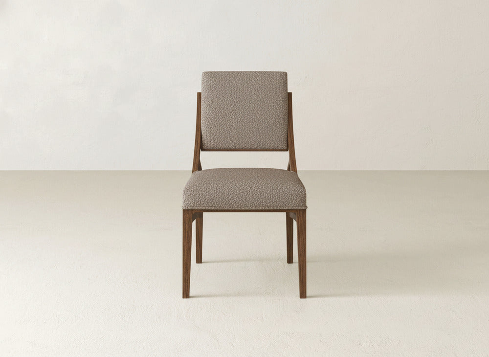 The Quinn Dining Chair by James+James features a modern upholstered design with a light brown seat and backrest, set against a simple, light background—ideal for enhancing your dining room decor.