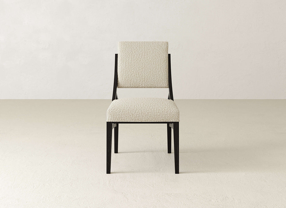 The Quinn Dining Chair by James+James features a modern upholstered, off-white seat and backrest with a dark wooden frame, ideal for enhancing your dining space against light-colored decor.