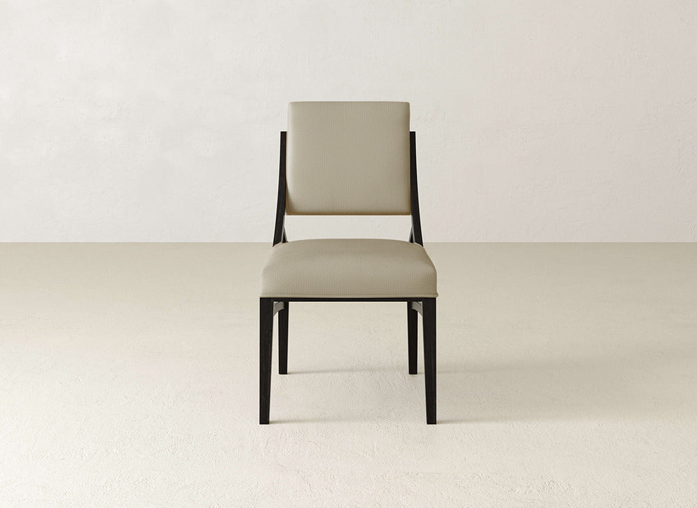 The Quinn Dining Chair by James+James features a modern, minimalist design with a light beige cushioned seat and backrest, plus a sleek black frame—an ideal centerpiece to enhance your dining room decor.