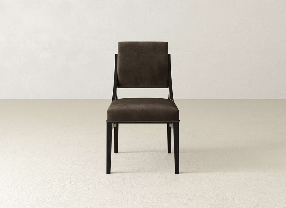 The James+James Quinn Dining Chair boasts a dark brown upholstered seat and back, black wooden legs, and a sleek design—ideal for enhancing your dining room’s elegance, especially paired with light-colored decor.