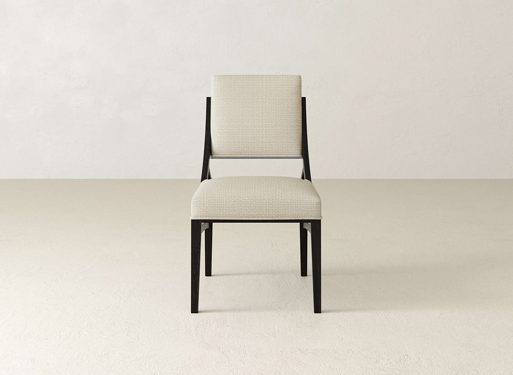 The Quinn Dining Chair by James+James features a light beige cushioned seat and backrest with a sleek black wooden frame—an elegant upholstered piece that enhances any dining room, especially in light, minimalist spaces.