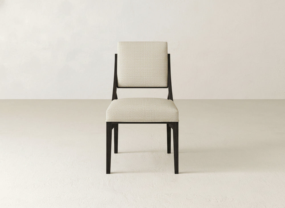 The Quinn Dining Chair by James+James features a modern upholstered seat and backrest with dark wooden legs, set against a light background—ideal for enhancing your dining room decor.