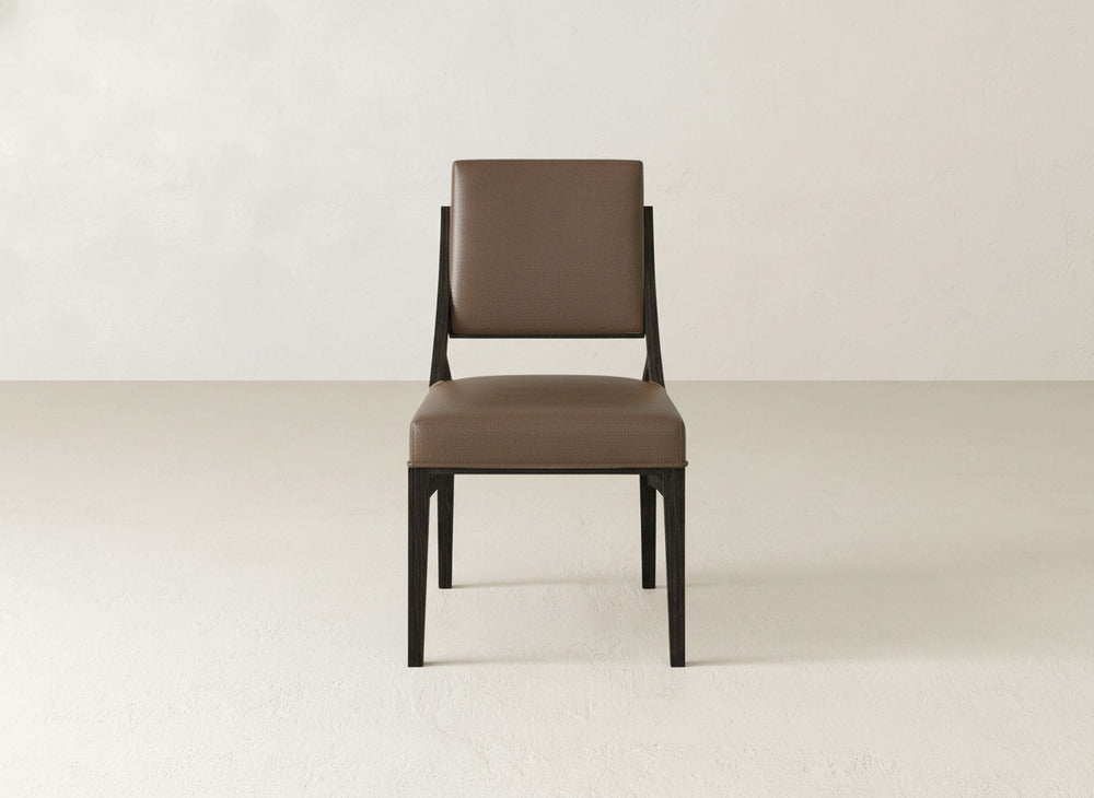 The Quinn Dining Chair by James+James features a dark wooden frame with brown upholstered seat and backrest, set on a light floor against an off-white wall—an ideal modern touch for your dining room decor.