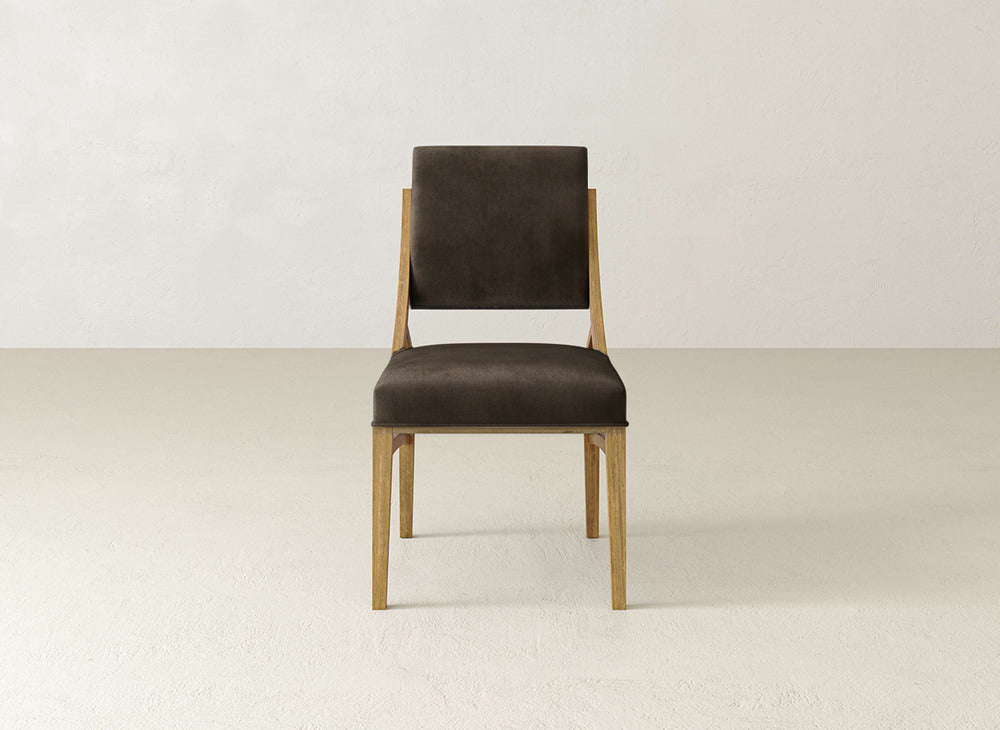 The Quinn Dining Chair by James+James features a dark brown cushioned seat and backrest, making it an ideal modern dining chair. Its simple wooden design contrasts beautifully with light flooring and off-white walls.