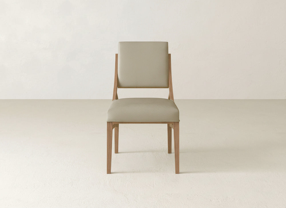 The Quinn Dining Chair by James+James features a modern wooden frame with a light beige upholstered seat and backrest, making it an ideal choice to enhance your dining space against any neutral backdrop.