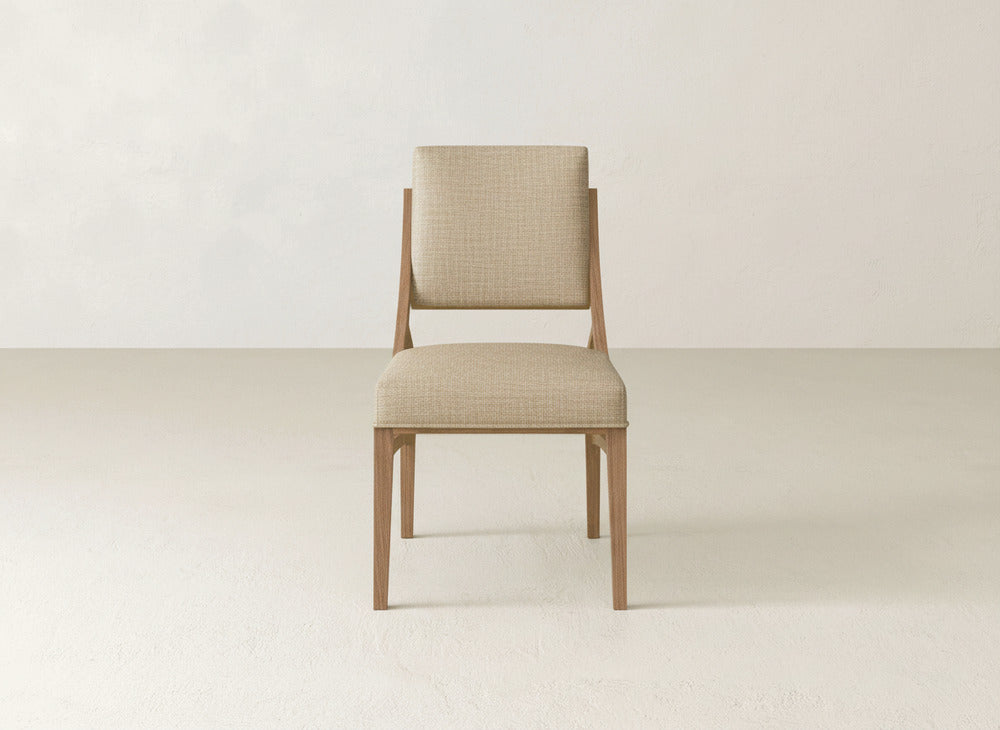 The Quinn Dining Chair by James+James features a light beige upholstered seat and backrest, shown facing forward against a neutral background—an elegant addition to any refined dining room decor.