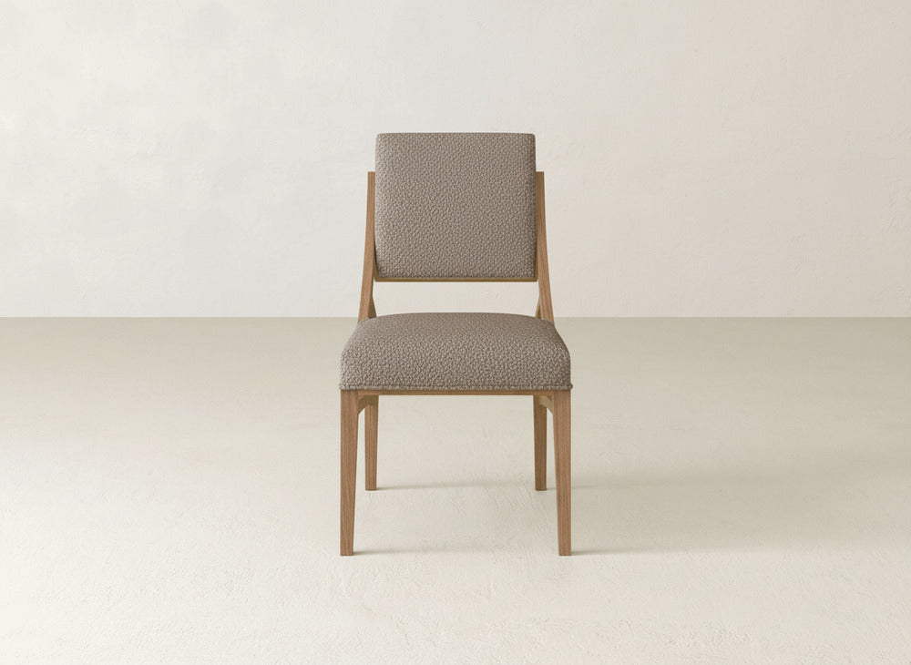 The Quinn Dining Chair by James+James features a light brown wooden frame and textured beige upholstery, creating a stylish look that complements any dining room décor.