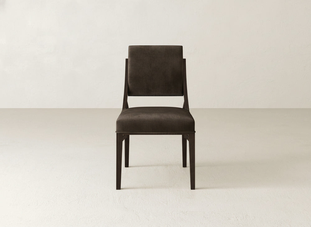 The James+James Quinn Dining Chair features dark brown upholstery, a rectangular backrest and seat, and wooden legs—its minimalist design is ideal for enhancing dining rooms with light-colored walls and floors.
