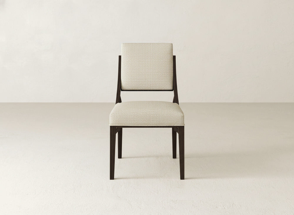The Quinn Dining Chair by James+James features a dark wooden frame with light, textured fabric on the seat and backrest, ideal for elevating your dining room. Shown against a simple off-white background.
