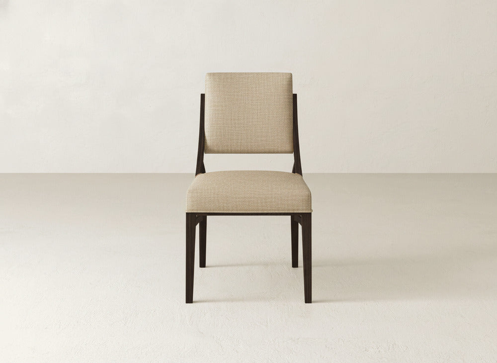 The Quinn Dining Chair by James+James features beige upholstery, a rectangular backrest, and dark wooden legs—perfect for enhancing your dining space, shown centered against a plain light backdrop.