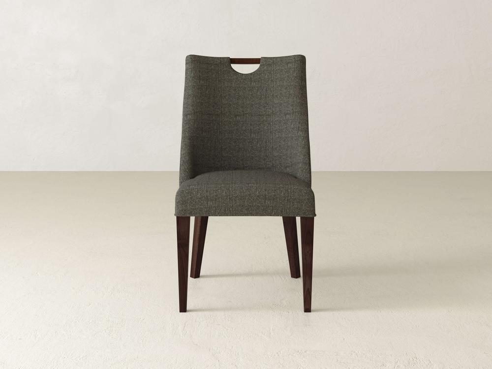 The Rosalie Dining Chair by James & James combines modern elegance with gray upholstery and a sturdy wooden frame. Its dark wooden legs pair well with light floors, while a cut-out handle on the back adds charm against off-white walls.