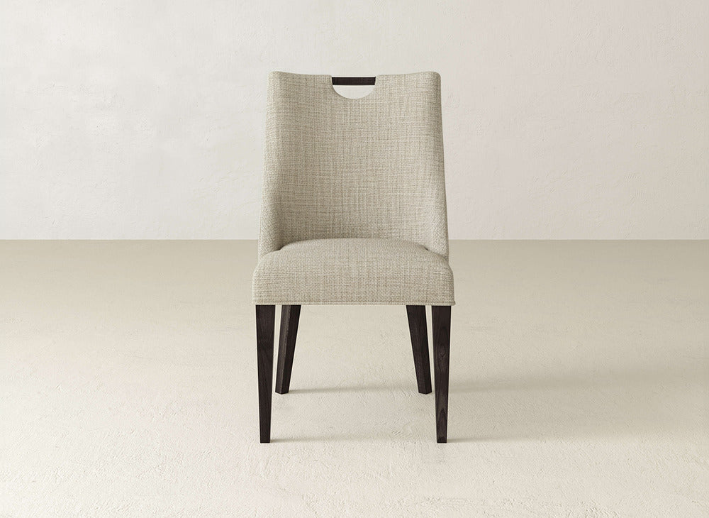 The Rosalie Dining Chair by James & James showcases light beige upholstery and dark wooden legs, set on a plain light floor with an off-white wall backdrop.