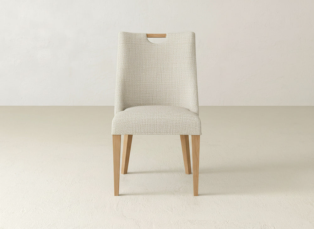 The Rosalie Dining Chair by James & James features light wooden legs and a textured off-white upholstered seat and backrest, ideal for minimalist spaces with light walls and floors.