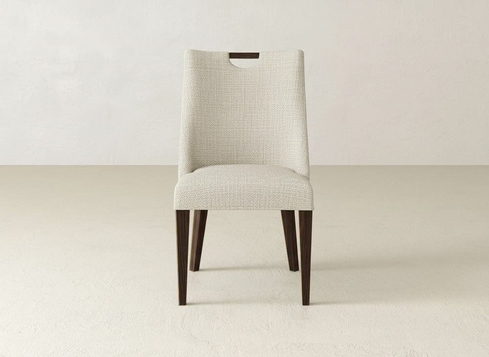 The James & James Rosalie Dining Chair showcases cream upholstery, a rectangular backrest with a notch, and dark wood legs—ideal for modern decor.