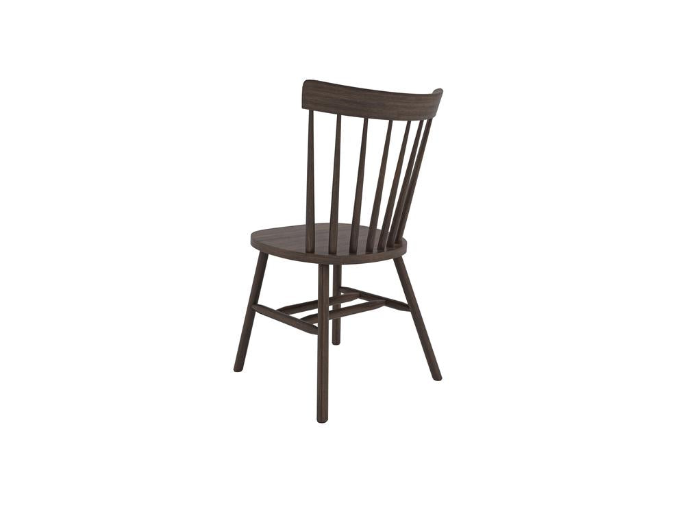 The Rustic Windsor Dining Chair - Tobacco by James+James is displayed from a slight side angle. This wooden dining chair showcases a rounded seat, straight legs, and a backrest composed of multiple vertical slats for support.