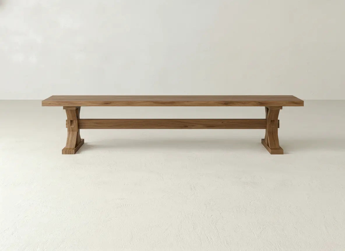 The James+James Trestle Bench - Oat on Oak features a long, rectangular oak design with sturdy legs and minimalist style, set against a plain white wall on a light-colored floor.